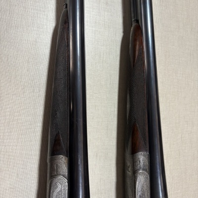 Duas espingardas de canos duplos com madeira escura e metal gravado