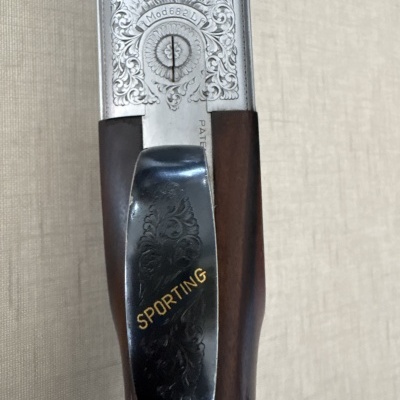 Detalhe de espingarda com gravações e a palavra SPORTING em metal preto