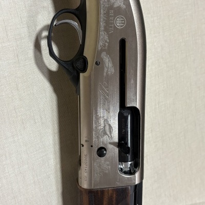 Espingarda Beretta com cabo em madeira e corpo metálico com gravuras e texto.