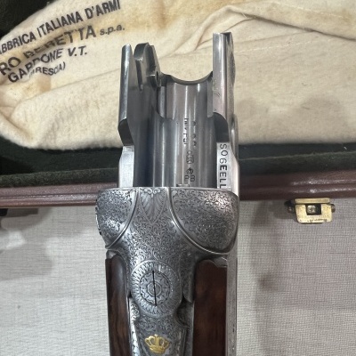 Parte superior de arma de fogo gravada em metal prateado com madeira e estojo de tecido claro