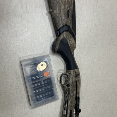 Espingarda com coronha camuflada e caixa de acessórios em fundo cinza