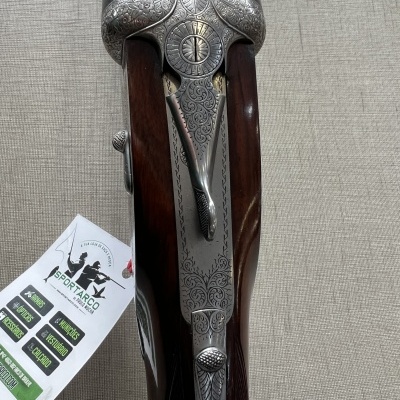 Espingarda de canos duplos em metal gravado e madeira escura com etiqueta de marca SPORTARCO ao lado