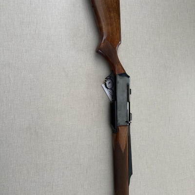 Espingarda de caça com madeira castanha e metal preto sobre fundo cinza