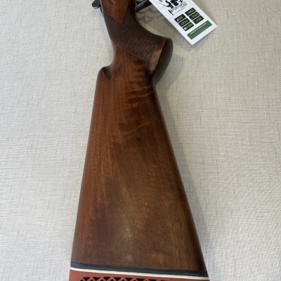 Coronha de espingarda em madeira com proteção vermelha e etiqueta pendurada