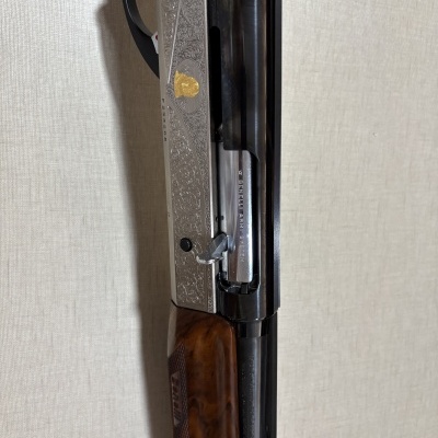Espingarda Benelli com empunhadura em madeira e detalhes metálicos gravados