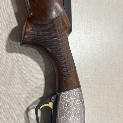 Parte inferior de arma de fogo em madeira, metal gravado e guarda-mato preto com gatilho dourado