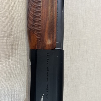 Espingarda com cabo de madeira castanha e corpo metálico preto com gravação e imagem