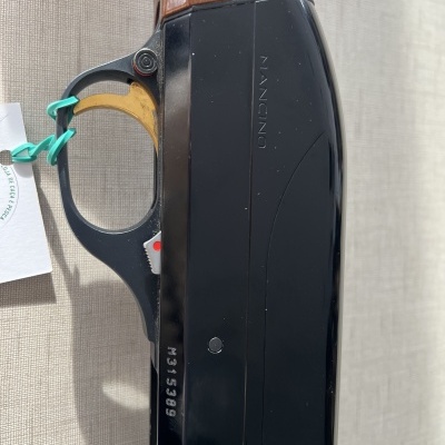 Arma de fogo com cabo em madeira e corpo metálico preto com inscrições NANCION e M315399