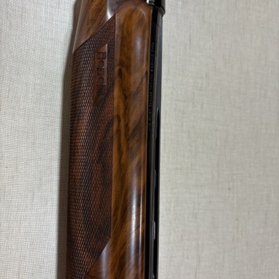 Espingarda de caça com punho em madeira e detalhes em metal sobre fundo beige texturizado