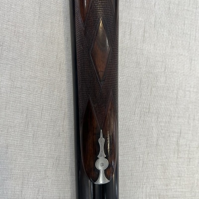 Cabo de arma em madeira escura com entalhes geométricos e detalhe metálico
