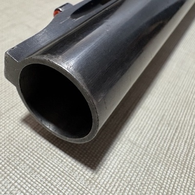 Peça tubular metálica preta apoiada em tecido bege claro