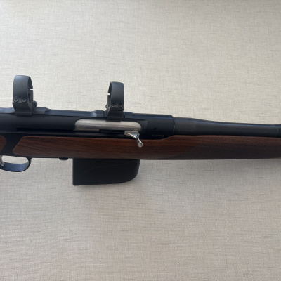 Rifle com coronha de madeira e cano metálico preto, com argolas para luneta e mira dianteira amarela