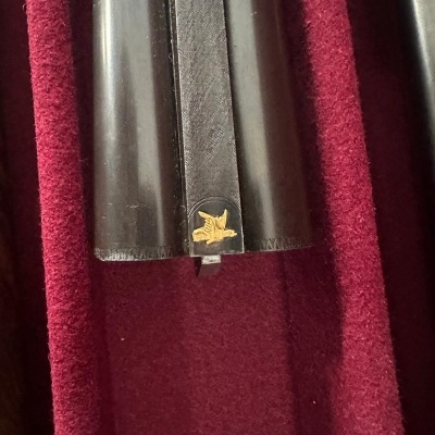 Estojo negro com emblema dourado em tecido vermelho