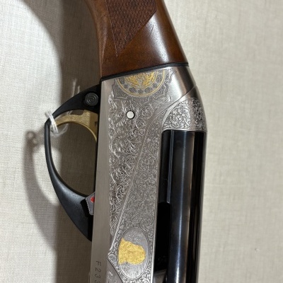 Região da empunhadura e caixa metálica com gravuras de uma arma de fogo