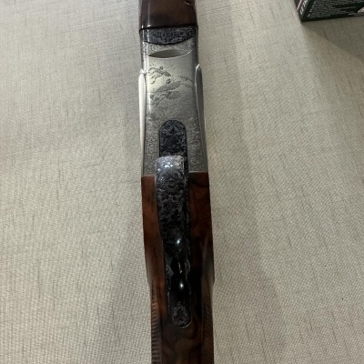 Arma de fogo com detalhes em madeira e metal gravado sobre tecido cinza