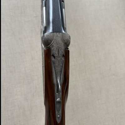 Espingarda de canos duplos com acabamento em metal prateado gravado e madeira escura texturada