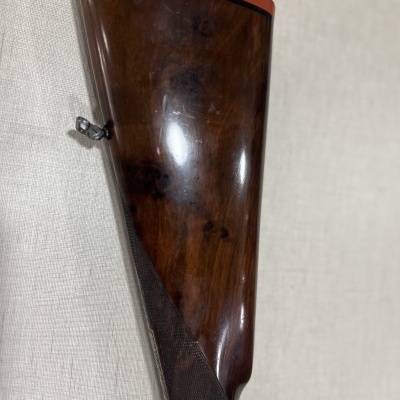 Parte traseira da coronha de espingarda em madeira castanha com calço vermelho