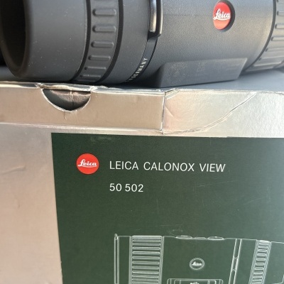 Telescópio monocular preto Leica Calonox View com caixa verde e cinza com texto e logo Leica.