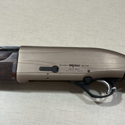 Detalhe lateral de uma espingarda com madeira e metal, texto A400 Xplor 12 GA action
