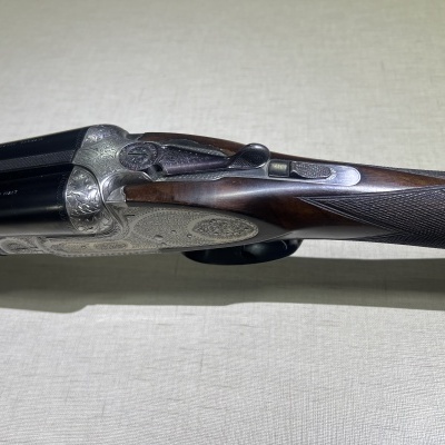 Espingarda de canos duplos com detalhes em madeira e metal, sobre fundo claro