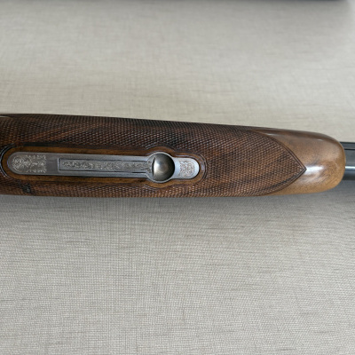 Parte de madeira polida de arma com inserções metálicas gravadas e textura quadriculada