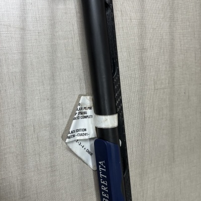 Arma de fogo Beretta com acabamento em preto fosco e azul, etiqueta com texto em inglês