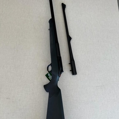 Arma de fogo de cano longo preto com cano adicional separado sobre superfície clara