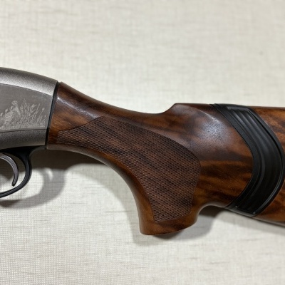 Parte de arma de fogo com madeira escura e metal cinzento gravado