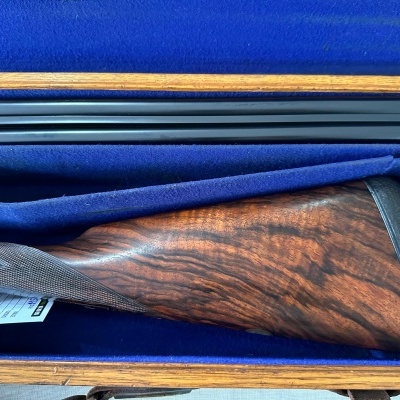 Coronha de espingarda em madeira escura dentro de caixa azul