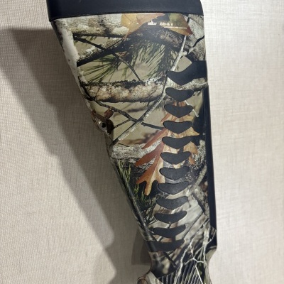 Parte traseira de arma camuflada com padrão em verde, castanho e preto