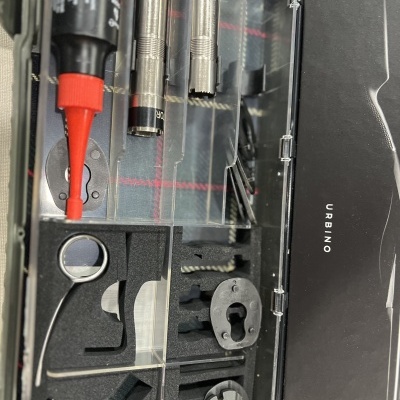 Estojo preto com peças metálicas e embalagem de cola vermelha da URBINO