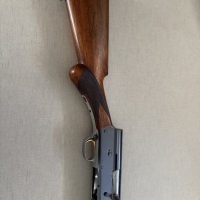 Espingarda com madeira castanha e metal cinza em fundo claro