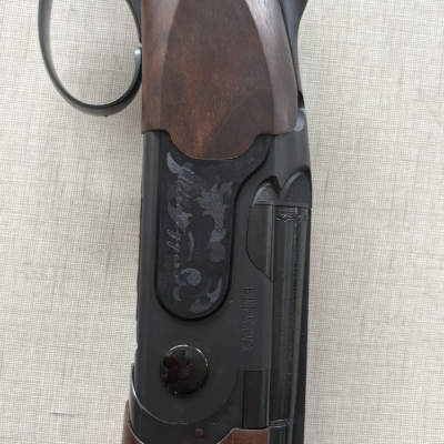 Espingarda com madeira castanha e metal preto gravado colocada sobre tecido bege