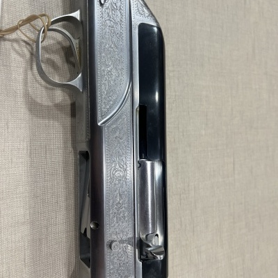 Espingarda prateada com detalhes gravados e madeira escura