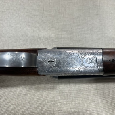 Espingarda com madeira castanha e metal gravado sobre tecido bege