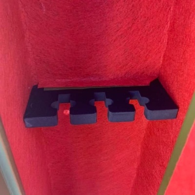 Estrutura interna vermelha aveludada com peça preta de espuma com recortes