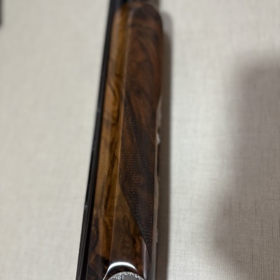 Parte frontal de espingarda com madeira castanha e metal prateado gravado