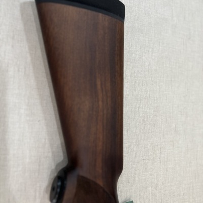 Coronha de espingarda em madeira castanha com ponta preta contra fundo claro