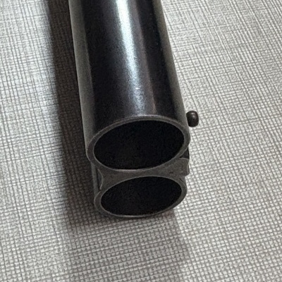 Cano duplo de metal preto sobre superfície cinza com padrão