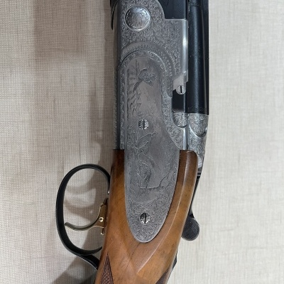Espingarda de caça com empunhadura em madeira e detalhes metálicos gravados