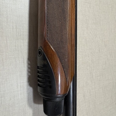 Parte de empunhadura de espingarda de madeira com detalhe preto e texto BERETTA