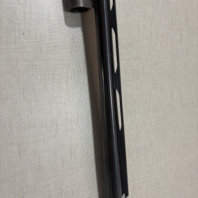 Detalhe do cano de uma arma de fogo preta contra parede bege texturada