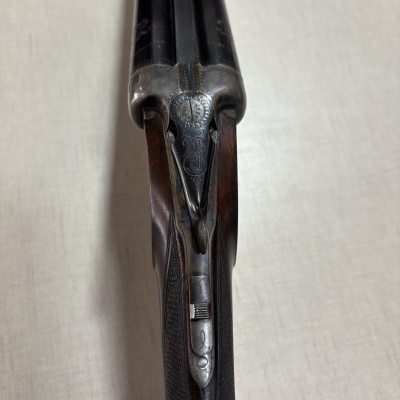 Espingarda dupla com madeira escura e detalhes metálicos gravados