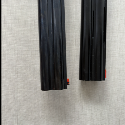 Duas peças pretas de plástico com detalhe vermelho sobre superfície bege texturizada