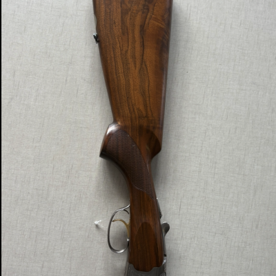 Parte traseira de espingarda com coronha de madeira castanha e detalhes metálicos gravados