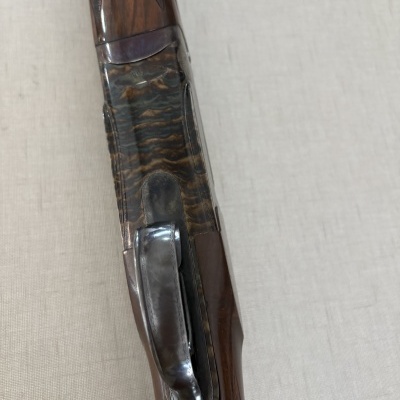 Parte de uma arma de fogo de madeira com detalhes metálicos