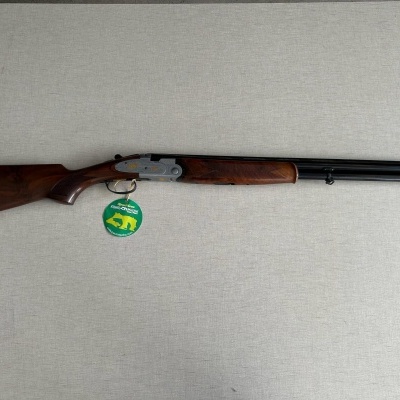 Espingarda de canos paralelos com madeira castanha e canos pretos sobre superfície cinzenta