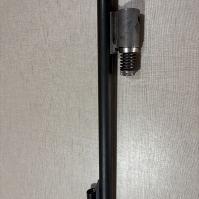 Tubulação preta com suporte de metal e mola em fundo cinza claro