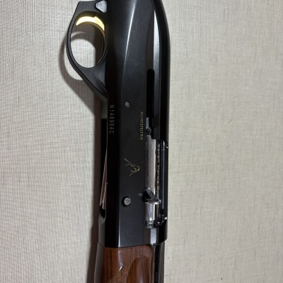 Espingarda com coronha em madeira e partes metálicas pretas e prateadas