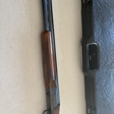 Espingarda com madeira e metal junto a caixa preta texturizada